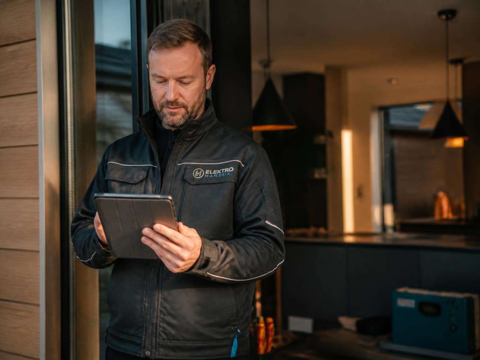Handwerker prüft auf einer Baustelle neue Auftragsanfragen auf dem Tablet
